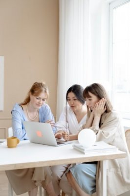three people sitting around  a desk in an office 